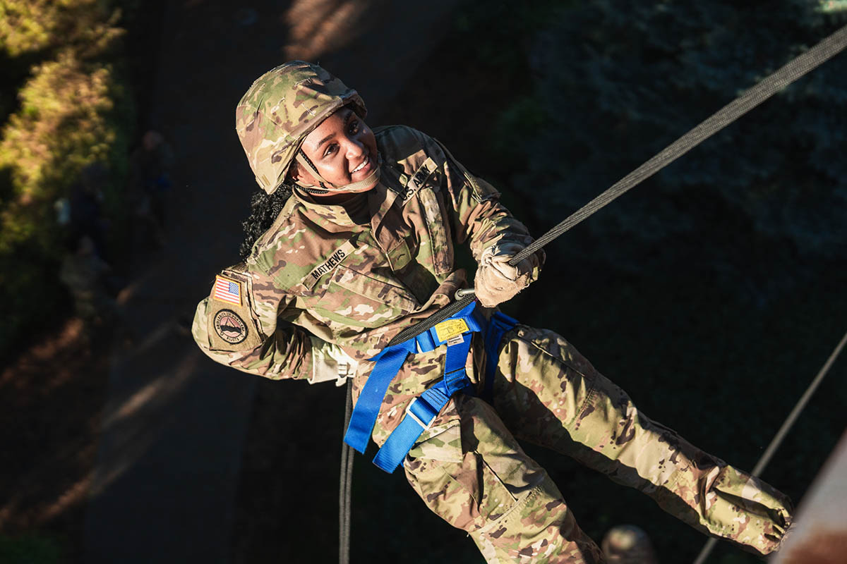 Smiling ROTC student rapelling down the outer wall of a building on the University of Portland campus