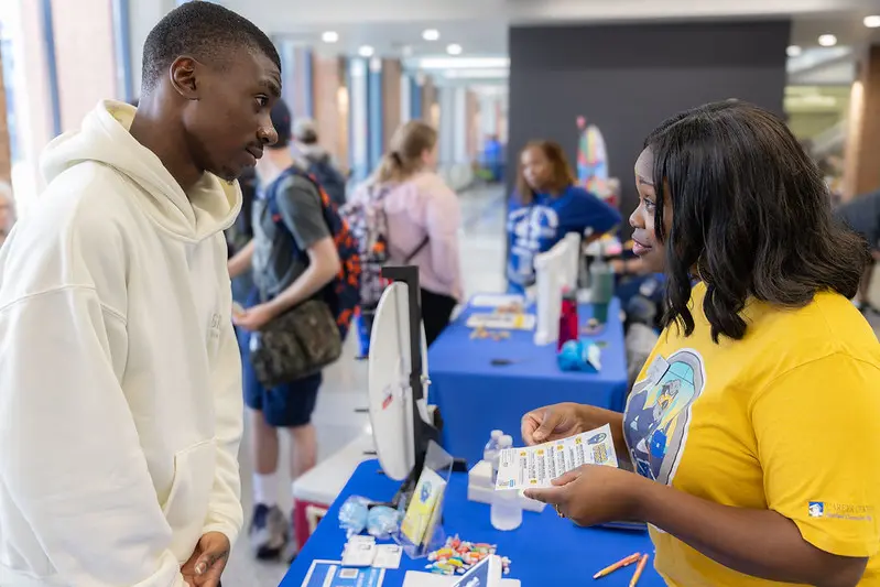 Student speaking with a staff member at a resource table