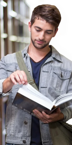 student standing in library looking at a book